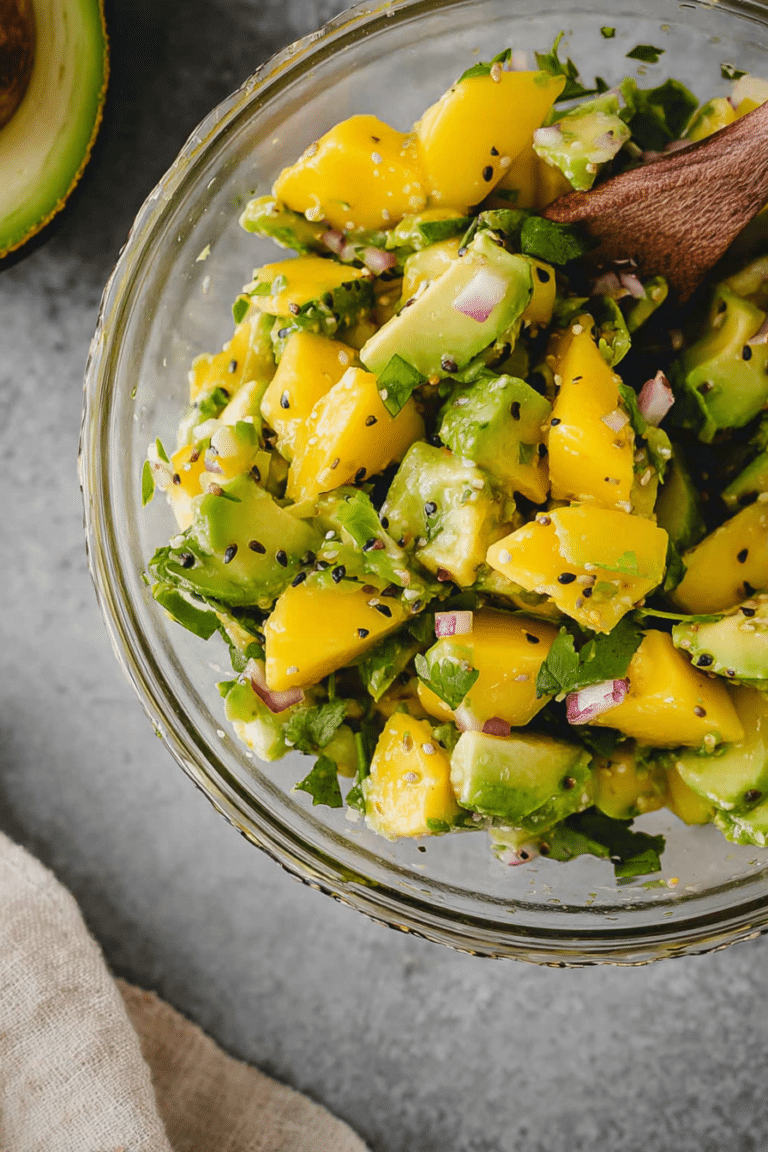 Frischer Mango Avocado Salat serviert in einer Schüssel, garnished mit Koriander und roten Zwiebeln.
