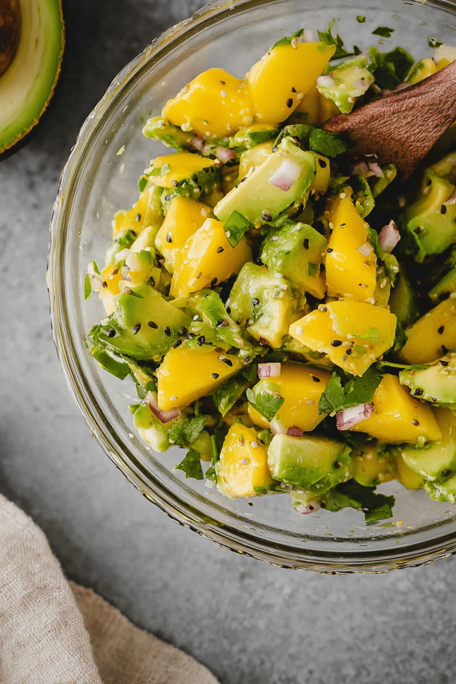 Frischer Mango Avocado Salat serviert in einer Schüssel, garnished mit Koriander und roten Zwiebeln.