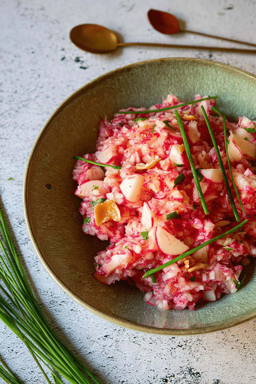 Frischer Radieschensalat mit Apfel, Walnüssen und Schnittlauch auf Holzbrett