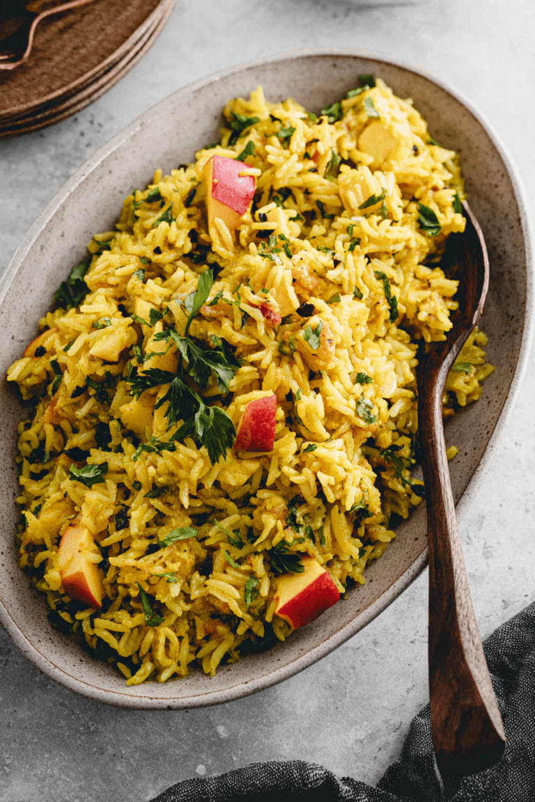 Reissalat mit Curry, Nektarinen und Mandeln auf einem Holzuntergrund.