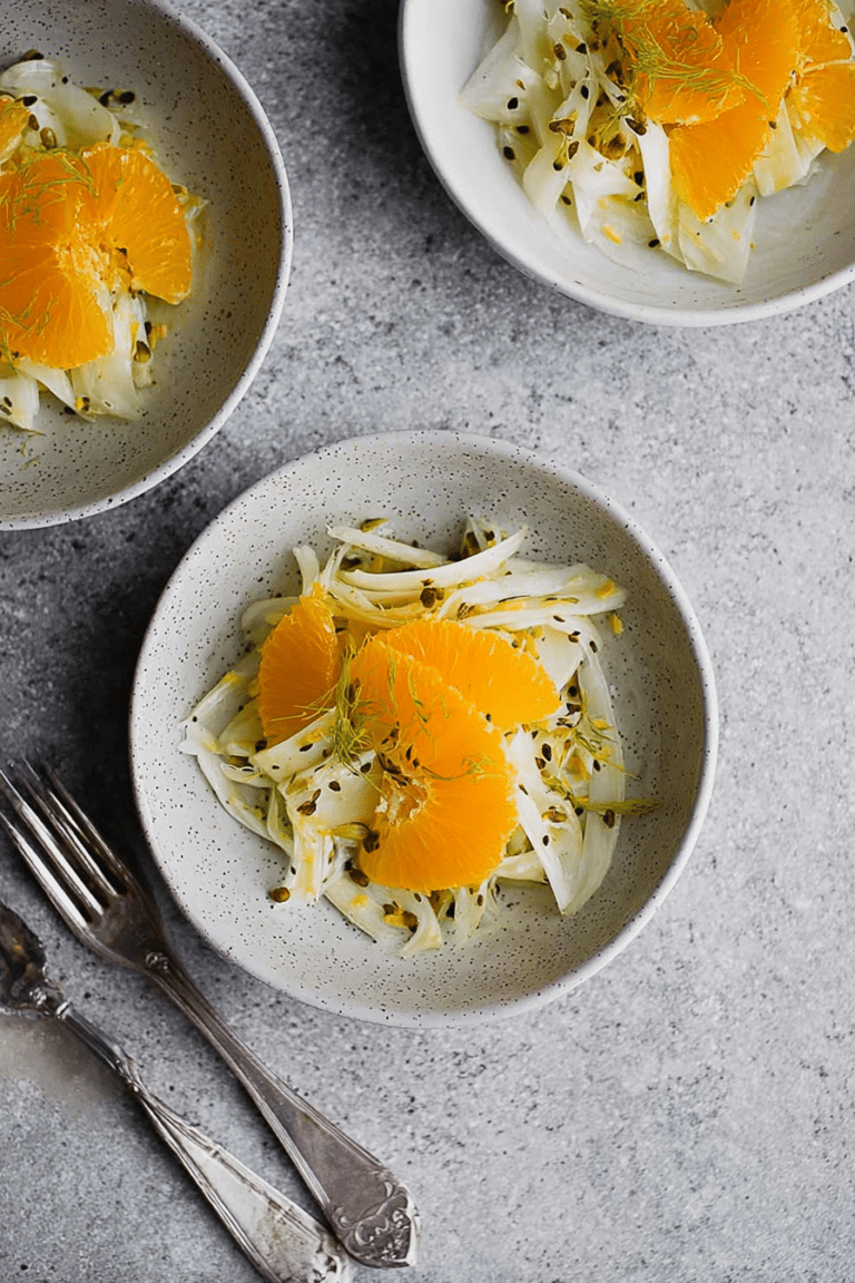 Fenchel Orangen Salat mit gerösteten Haselnüssen auf einem Holztisch serviert.