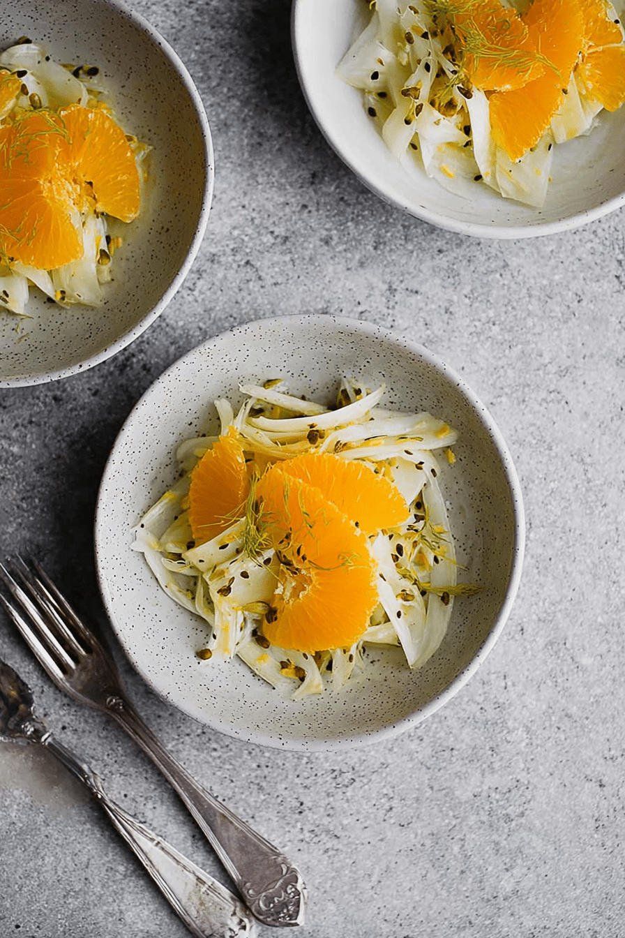 Fenchel Orangen Salat mit gerösteten Haselnüssen auf einem Holztisch serviert.