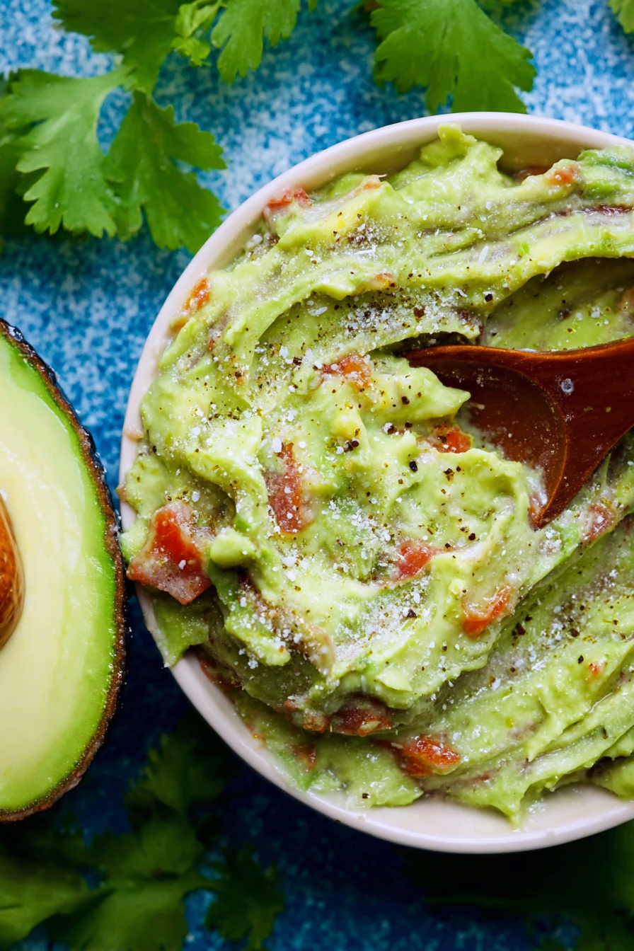 Frischer Avocado-Dip in einer Schüssel, dekoriert mit Koriander und Limetten, ideale Snack-Darstellung.