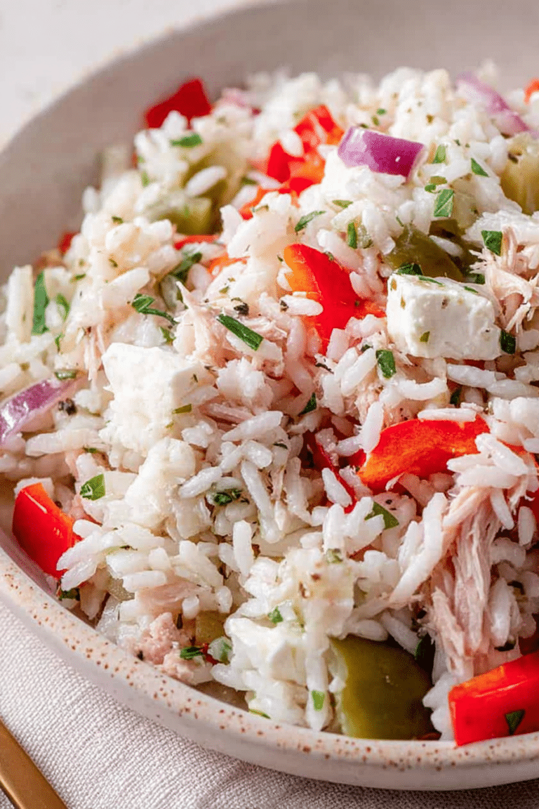 Frischer Reissalat mit Thunfisch, Paprika und Feta in einer Schüssel, dekoriert mit frischen Kräutern.