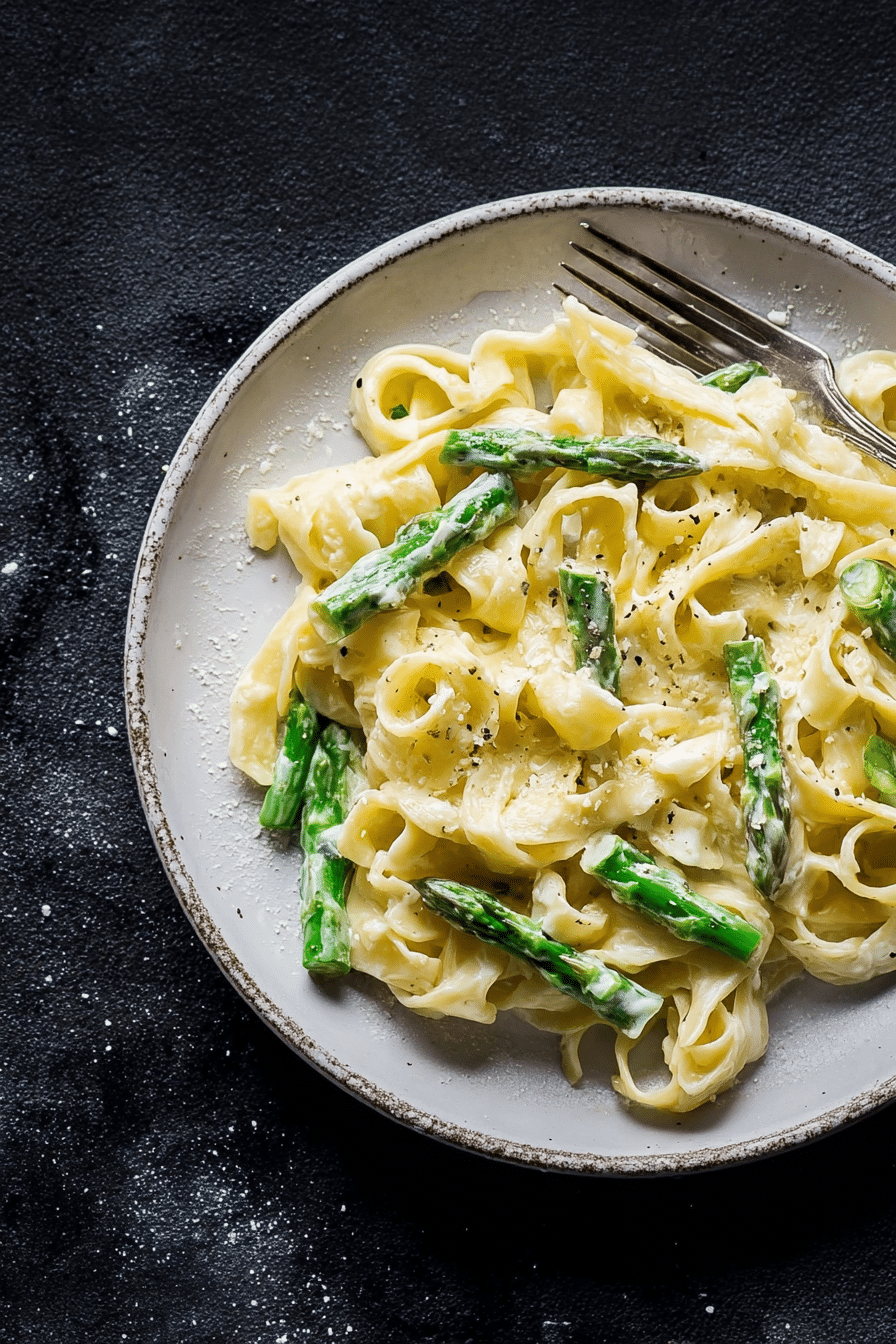 Frischkäse-Pasta mit grünem Spargel auf dem Tisch, umgeben von frischen Zutaten.