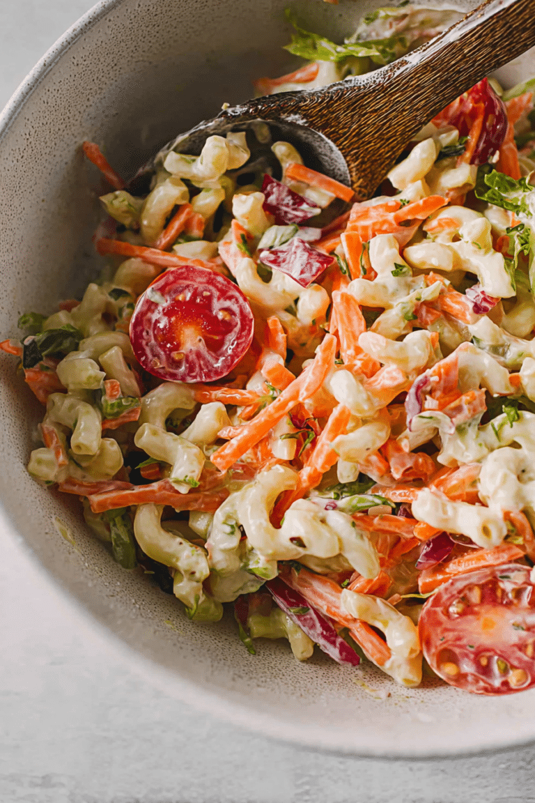 Hörnlisalat mit buntem Gemüse und cremigem Dressing in einer Schüssel, serviert auf einem Holztisch.