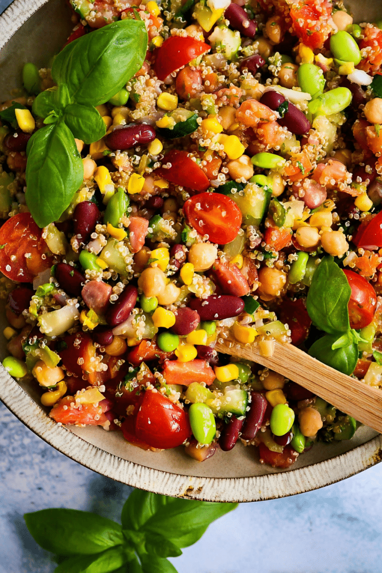 Bunter Hülsenfrüchte Salat mit Quinoa, Tofu, und frischem Gemüse auf Holztisch.