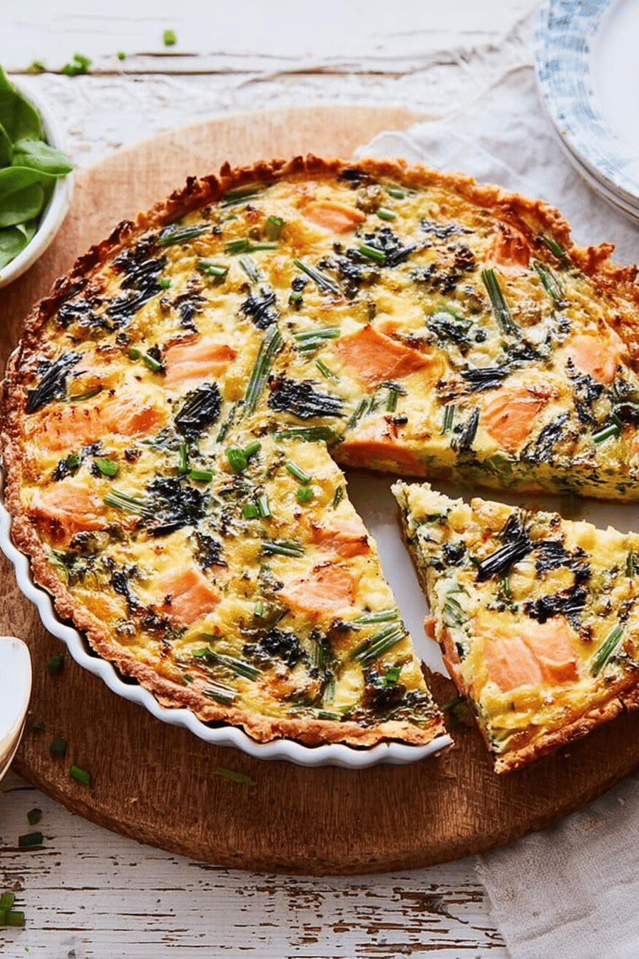 Frisch gebackene Lachs-Bärlauch-Quiche auf einem Holztisch, umgeben von frischen Bärlauchblättern und Lachs, die appetitlich aufgeschnitten ist.