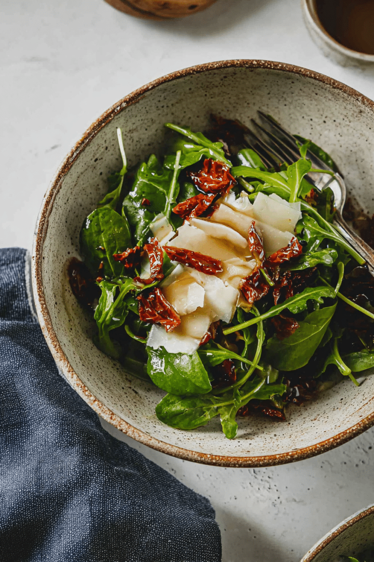 Rucola Salat mit getrockneten Tomaten und Parmesan auf einem Holztisch