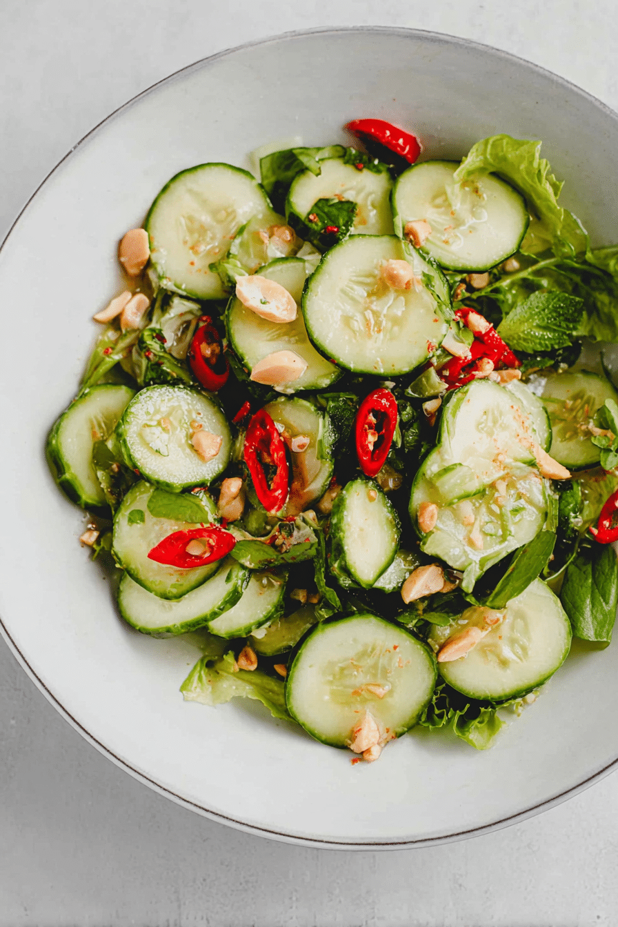 Frischer Thai Gurkensalat mit Erdnüssen und Koriander auf einem Holztisch.