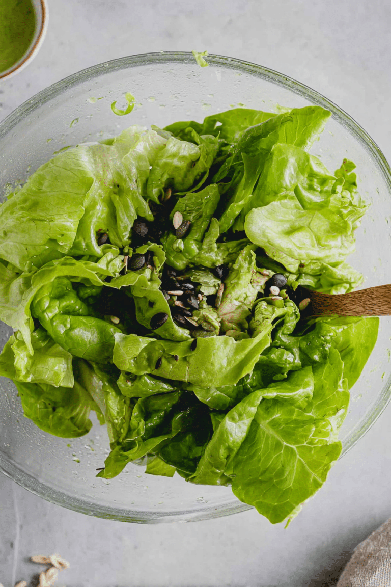 Frischer Kopfsalat mit Dressing und Schalotten in einer Schüssel.