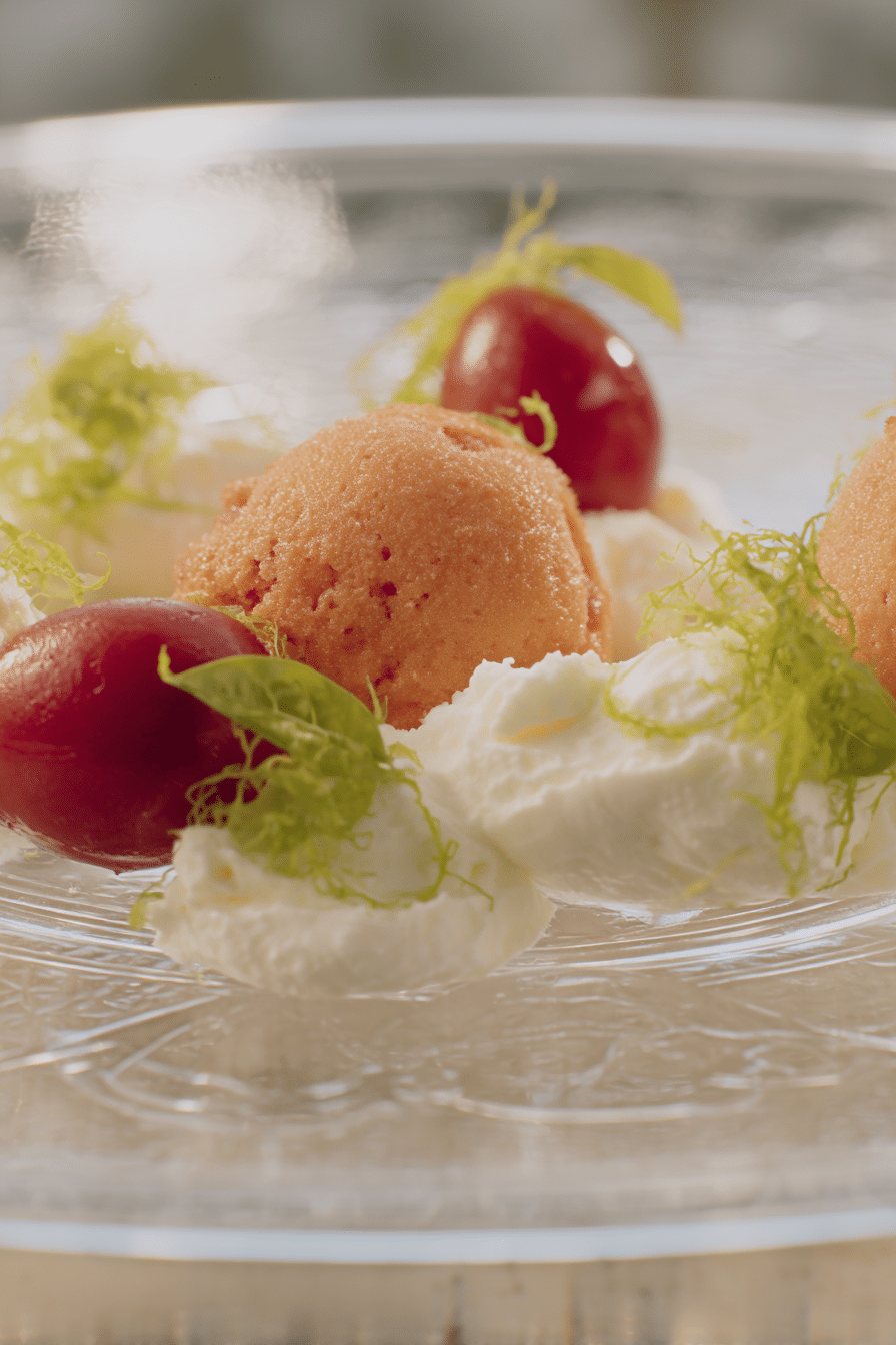 Gourmet-Tomatensalat mit Mozzarella und Olivenölsorbet, dekoriert mit frischen Kräutern und essbaren Blumen.