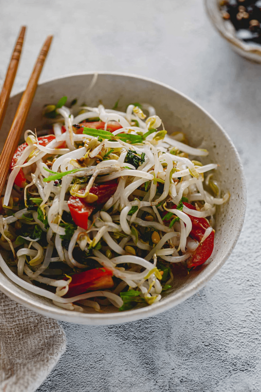 Sojasprossensalat mit Frühlingszwiebeln und Chili an einem asiatischen Hintergrund.