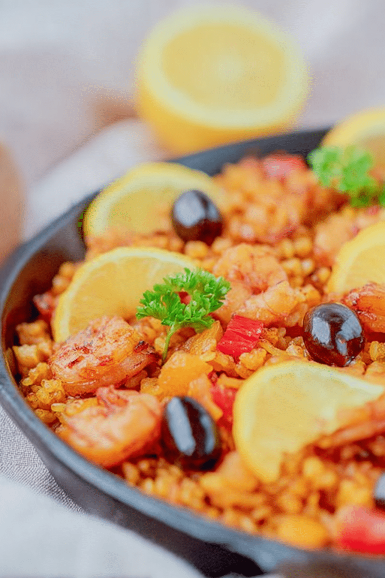Vegane Paella mit Tofu, buntem Gemüse und Zitronenscheiben, serviert in einer Schüssel.