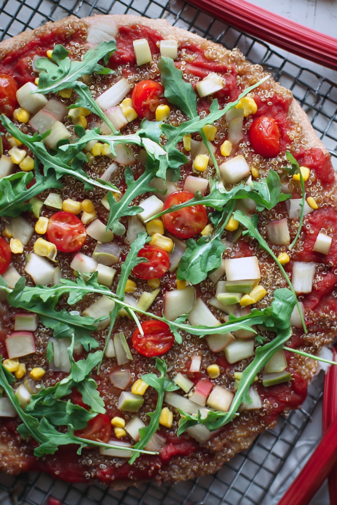 Vegane Quinoa-Pizza mit glutenfreier Kruste und buntem Gemüse auf einem Holzbrett.