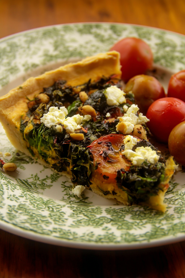 Frisch gebackene Wintergemüse Quiche mit Mangold, Rote Beete und anderen winterlichen Gemüsesorten auf einem rustikalen Tisch.
